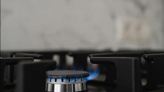 Modern kitchen stove, natural gas burns with a blue flame. Household gas consumption. Close-up, selective focus