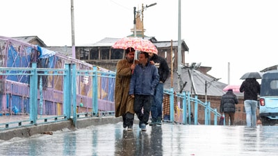 Srinagar, 03: People holding an umbrella pass on a road amid rains, in Srinagar on Monday. (ANI Photo/Basit Zargar) Srinagar, 03: People holding an umbrella pass on a road amid rains, in Srinagar on Monday. (ANI Photo/Basit Zargar)