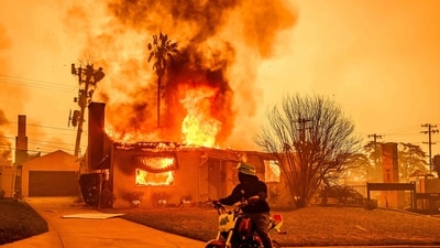 Fueled by strong winds and dry weather, a series of fierce wildfires broke out on January 7 and raced through the Los Angeles region, burning hundreds of properties and killing many people, some of whom perished attempting to save their houses from the flames. In the picture: A motorcyclist stops to look at a burning home during the Eaton Fire in the Altadena area of Los Angeles County, California, on January 8, 2025. (AFP)