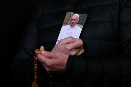 A person holds a picture of Pope Francis and a rosary during a prayer service at St. Peter's Square, as Pope Francis continues his hospitalization, at the Vatican, February 25, 2025. (Reuters)