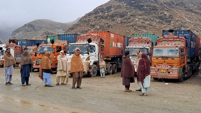 People stand next to parked trucks loaded with supplies at the Torkham border crossing following the closure of the border crossing between Pakistan and Afghanistan (File) (REUTERS)