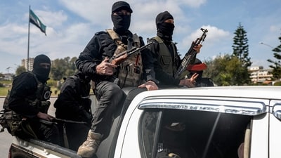 Security forces loyal to the interim Syrian government ride in the back of a vehicle moving along a road in Syria's western city of Latakia on March 9, 2025. (AFP) Security forces loyal to the interim Syrian government ride in the back of a vehicle moving along a road in Syria's western city of Latakia on March 9, 2025. (AFP)