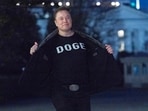 Elon Musk flashes his t-shirt that reads "DOGE" to the media as he walks on South Lawn of the White House, in Washington.