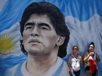 Members of social organizations stand next to a mural depicting late Argentine football star Diego Maradona during a protest at Pueyrredon bridge in Buenos Aires.