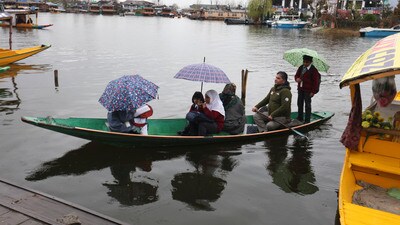 Students with umbrellas cross the Dal Lake during rain in Srinagar on Thursday. (Waseem Andrabi /HT)