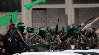 Palestinian Hamas fighters carry their guns in Nuseirat in the central Gaza Strip on February 22, 2025. (AFP) Palestinian Hamas fighters carry their guns in Nuseirat in the central Gaza Strip on February 22, 2025. (AFP)