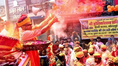 Uttar Pradesh Chief Minister Yogi Adityanath hurls coloured powder on people during a procession on the occasion of Holi, in Gorakhpur. (@myogioffice via PTI)