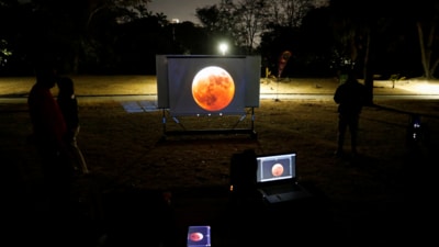 People watch on a video beam screen a full moon during a "Blood Moon" total lunar eclipse, at an overnight camp at the Humboldt Planetarium, in Caracas, Venezuela March 14, 2025. (Reuters) People watch on a video beam screen a full moon during a "Blood Moon" total lunar eclipse, at an overnight camp at the Humboldt Planetarium, in Caracas, Venezuela March 14, 2025. (Reuters)