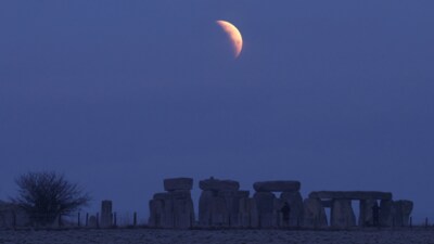 People view the full moon as a section moves into shadow during a lunar eclipse, before dawn, at Stonehenge stone circle, near Amesbury, southern Britain, March 14, 2025. (REUTERS) People view the full moon as a section moves into shadow during a lunar eclipse, before dawn, at Stonehenge stone circle, near Amesbury, southern Britain, March 14, 2025. (REUTERS)