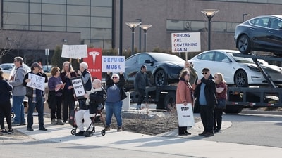 People participate in a protest against Elon Musk outside of a Tesla dealership in West Bloomfield, Michigan on March 13, 2025. (AFP) People participate in a protest against Elon Musk outside of a Tesla dealership in West Bloomfield, Michigan on March 13, 2025. (AFP)