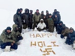 Border Security Force (BSF) personnel pose for a picture amid heavy snowfall atop a mountain as they celebrate the Holi festival, on Friday.
