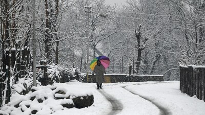 A man walks during snowfall at Gund village of district Ganderbal,some 75 kms from Srinagar on 15 March 2025. (.(Photo By Waseem Andrabi /Hindustan Times)--)