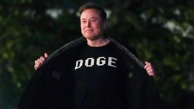 Elon Musk shows off a shirt that says "DOGE" as he walks on the South Lawn of the white Housein Washington, DC on March 9, 2025. (AFP) Elon Musk shows off a shirt that says "DOGE" as he walks on the South Lawn of the white Housein Washington, DC on March 9, 2025. (AFP)