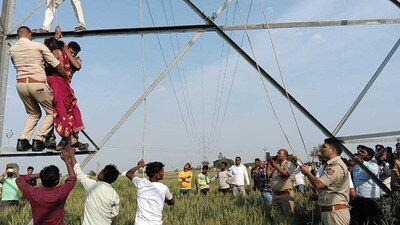 Woman on top of the high tension line tower being brought down by constables and lineman on Monday afternoon. (HT)