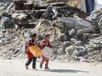 Palestinian children walk past rubble as people make their way to flee their homes, after the Israel army issued evacuation orders for a number of neighborhoods, following heavy Israeli strikes, in Beit Lahiya.