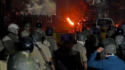 Members of police stand as vehicles burn after clashes erupted due to demands over removal of the tomb of Mughal emperor Aurangzeb, in Nagpur, India, March 17, 2025. REUTERS/Stringer (REUTERS)