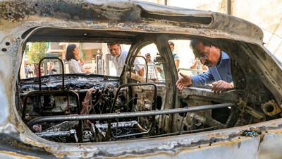 People stand near charred remains of a car at Chitnis Park area amid curfew after violence erupted on Monday night, in Nagpur, Tuesday, March 18, 2025. Curfew has been imposed in several areas of Maharashtra's Nagpur city after a protest against Mughal emperor Aurangzeb's tomb triggered violence. (PTI) People stand near charred remains of a car at Chitnis Park area amid curfew after violence erupted on Monday night, in Nagpur, Tuesday, March 18, 2025. Curfew has been imposed in several areas of Maharashtra's Nagpur city after a protest against Mughal emperor Aurangzeb's tomb triggered violence. (PTI)