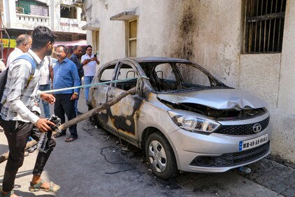 People stand near charred remains of a car at Chitnis Park area amid curfew after violence erupted on Monday night in Nagpur on Tuesday, (PTI) People stand near charred remains of a car at Chitnis Park area amid curfew after violence erupted on Monday night in Nagpur on Tuesday, (PTI)