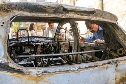 People stand near charred remains of a car at Chitnis Park area amid curfew after violence erupted on Monday night, in Nagpur, Tuesday. (PTI) People stand near charred remains of a car at Chitnis Park area amid curfew after violence erupted on Monday night, in Nagpur, Tuesday. (PTI)