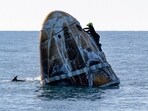A support team member works on the SpaceX capsule shortly after it landed with NASA astronauts Nick Hague, Sunita Williams, Butch Wilmore, and Russia's Alexander Gorbunov aboard as a dolphin swims past in the water off the coast of Tallahassee, Florida, on Tuesday, March 18, 2025. A support team member works on the SpaceX capsule shortly after it landed with NASA astronauts Nick Hague, Sunita Williams, Butch Wilmore, and Russia's Alexander Gorbunov aboard as a dolphin swims past in the water off the coast of Tallahassee, Florida, on Tuesday, March 18, 2025.