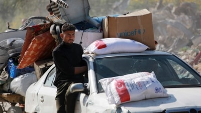 A Palestinian man sits on the window opening of a car, packed with personal belongings and food as families leave the eastern sector of the Gaza Strip, following Israeli airstrikes. (AFP) A Palestinian man sits on the window opening of a car, packed with personal belongings and food as families leave the eastern sector of the Gaza Strip, following Israeli airstrikes. (AFP)