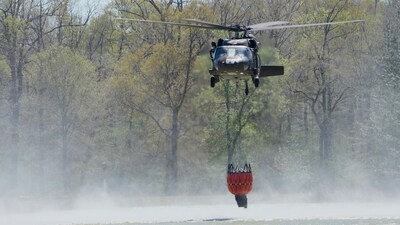 A helicopter drops a bucket to gather water to battle the Pauline Road wildfire Thursday, March 20, 2025, in Cleveland, Texas. (AP) A helicopter drops a bucket to gather water to battle the Pauline Road wildfire Thursday, March 20, 2025, in Cleveland, Texas. (AP)