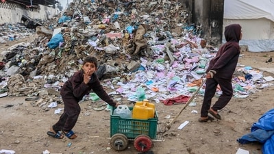 A displaced Palestinian child gestures as he pushes a cart carrying water containers near a camp set up at a landfill in the Yarmuk area in Gaza City on March 20, 2025. (AFP) A displaced Palestinian child gestures as he pushes a cart carrying water containers near a camp set up at a landfill in the Yarmuk area in Gaza City on March 20, 2025. (AFP)
