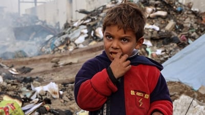 A boy looks on as he eats at a camp sheltering displaced Palestinians set up at a landfill in the Yarmuk area in Gaza City on March 20, 2025. (AFP) A boy looks on as he eats at a camp sheltering displaced Palestinians set up at a landfill in the Yarmuk area in Gaza City on March 20, 2025. (AFP)
