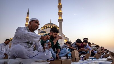 Muslim devotees gather for a fast-breaking iftar meal outside a mosque in the emirate of Sharjah, during the Muslim holy fasting month of Ramadan. (Photo by FADEL SENNA / AFP) Muslim devotees gather for a fast-breaking iftar meal outside a mosque in the emirate of Sharjah, during the Muslim holy fasting month of Ramadan. (Photo by FADEL SENNA / AFP)