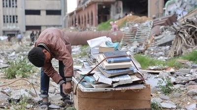 A displaced Palestinian collects books, from the destroyed Islamic University to use as fuel to cook food, in Gaza City. (AFP) A displaced Palestinian collects books, from the destroyed Islamic University to use as fuel to cook food, in Gaza City. (AFP)