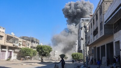 Palestinians looks at smoke billowing from Israeli strikes on a makeshift displacement camp in central Gaza City on March 23, 2025. (AFP) Palestinians looks at smoke billowing from Israeli strikes on a makeshift displacement camp in central Gaza City on March 23, 2025. (AFP)