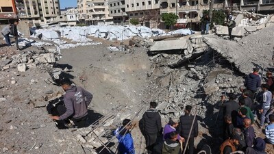 Palestinians inspect a crater at the site of Israeli strikes on a makeshift displacement camp in central Gaza City on March 23, 2025. (AFP) Palestinians inspect a crater at the site of Israeli strikes on a makeshift displacement camp in central Gaza City on March 23, 2025. (AFP)
