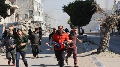Palestinians rush an injured girl away from the site of Israeli strikes on a makeshift displacement camp in central Gaza City on March 23, 2025. (AFP) Palestinians rush an injured girl away from the site of Israeli strikes on a makeshift displacement camp in central Gaza City on March 23, 2025. (AFP)