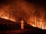A wildfire is seen next to a stone lantern of family tomb in Andong on March 26, 2025.. A wildfire is seen next to a stone lantern of family tomb in Andong on March 26, 2025..