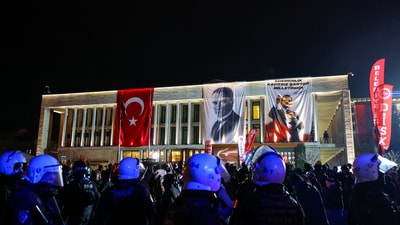 The demonstrations have expanded across the country, with activists, students, and supporters of the opposition uniting against what they describe as an attack on democracy. In pic: Police officers stand guard, as people take part in a protest against the arrest of Istanbul Mayor Ekrem Imamoglu as part of a corruption investigation, in front of the Istanbul Metropolitan Municipality building, in Istanbul, Turkey.  (REUTERS)