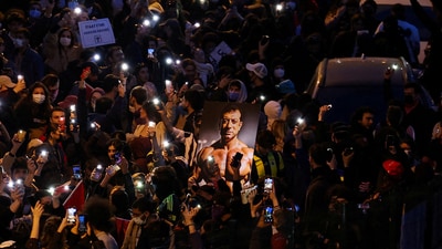 A person carries an image depicting Istanbul Mayor Ekrem Imamoglu as people flash mobile phone lights during a protest against the arrest of Imamoglu as part of a corruption investigation, in Istanbul.  (REUTERS)