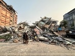 People stand near the debris of a collapsed building in Mandalay after the earthquake on March 28, 2025.