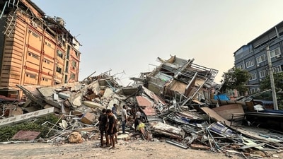People stand near the debris of a collapsed building in Mandalay after the earthquake on March 28, 2025. (AFP)