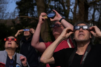 People observe a partial solar eclipse with special protective glasses, in London, Saturday. (AP)