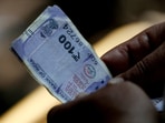 A customer holds hundred rupees Indian currency notes near a roadside currency exchange stall in New Delhi, India, May 24, 2024.