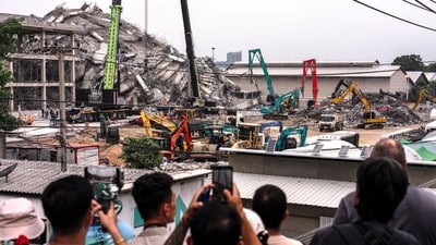 People take a picture as machinery is used to clear the rubble at the site of an under-construction building collapse in Bangkok on March 31, 2025. (AFP) People take a picture as machinery is used to clear the rubble at the site of an under-construction building collapse in Bangkok on March 31, 2025. (AFP)