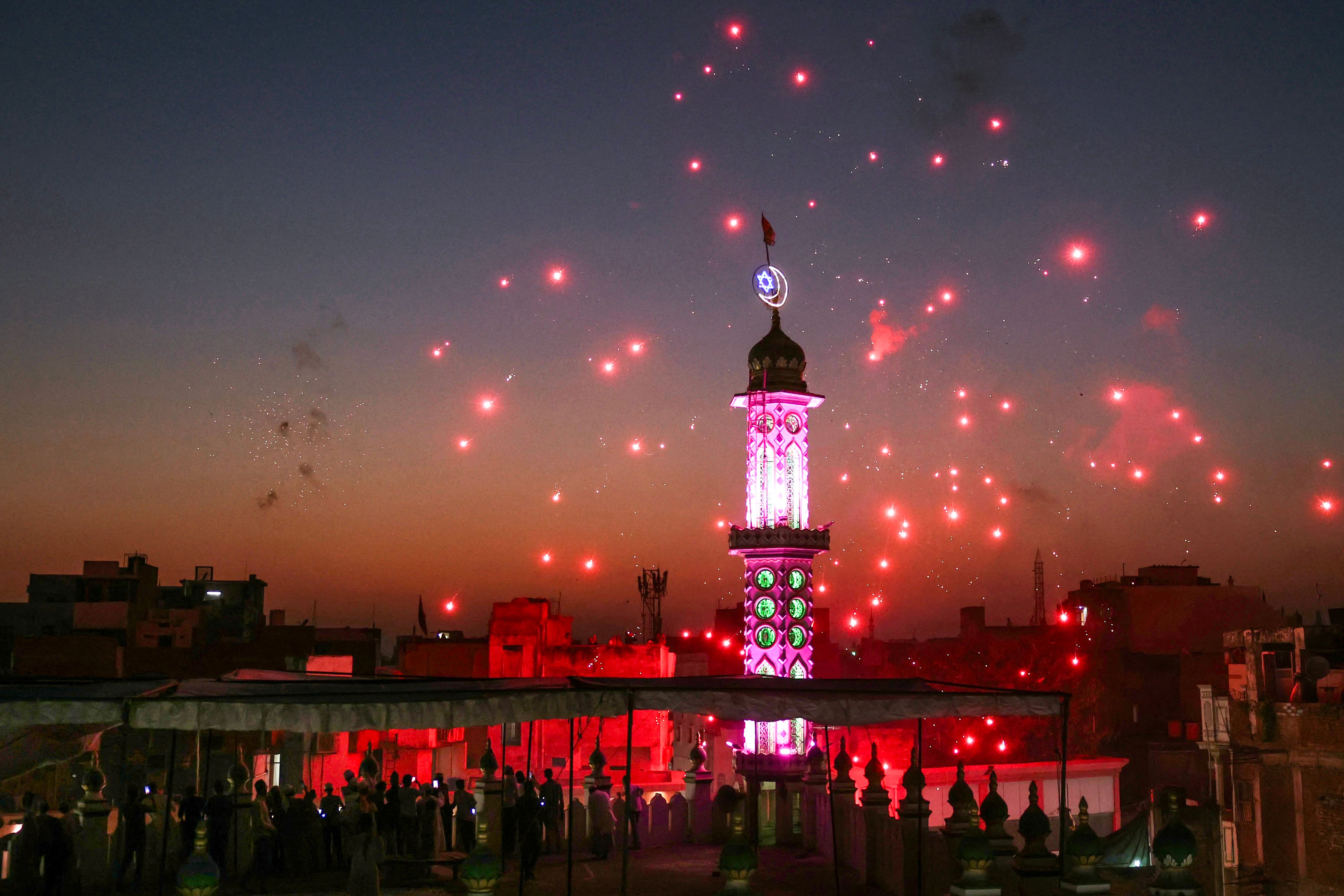 Muslim devotees take photos with their phones as the sky over the Langde Hafiz mosque is illuminated with fireworks, ahead of Eid al-Fitr, the festival marking the end of the Islamic holy month of Ramadan, in Varanasi on March 30, 2025. (AFP) Muslim devotees take photos with their phones as the sky over the Langde Hafiz mosque is illuminated with fireworks, ahead of Eid al-Fitr, the festival marking the end of the Islamic holy month of Ramadan, in Varanasi on March 30, 2025. (AFP)