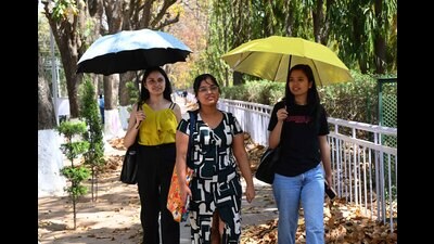 Students take shelter under umbrellas to beat the heat at Panjab University in Chandigarh on Wednesday. (Keshav Singh/HT)