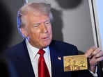 President Donald Trump holds up the $5 million gold card as he speaks to reporters while in flight on board Air Force One, en route to Miami, Thursday, April 3, 2025. (Pool via AP)