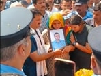 The parents and younger sister of flight lieutenant Siddharth Yadav holding his photo at his cremation in their native village of Majra Bhalkhi in Rewari district of Haryana on Friday. (HT Photo)