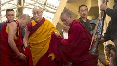The Dalai Lama is helped by monks as he leaves after leading a prayer session in Dharmsala. (HT Photo)