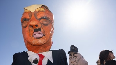 Demonstrators wear large papier mache likenesses of US President Donald Trump and his advisor, Tesl CEO Elon Musk outside the Minnesota State Capitol during the nationwide "Hands Off!" protest against their policies in St. Paul, Minnesota, on April 5, 2025.  (AFP)