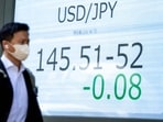 A man looks at an electronic board showing the foreign exchange trading price of the Japanese yen against the US dollar on a street in Tokyo on April 7, 2025.