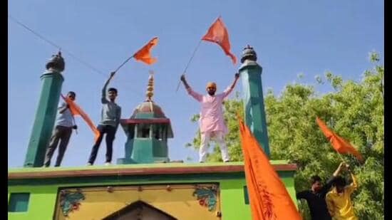 Activists of Maharaja Suheldev Samman Suraksha Manch holding saffron coloured flags atop the dargah of Syed Salar Masood Ghazi on Ram Navami in Baharia area of Prayagraj on Sunday. (Sourced)