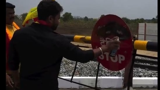 A Kannada activist painting the railway sign board with black paint.